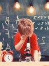 First former interested in studying, learning, education. Kid boy looks into microscope in classroom, chalkboard on