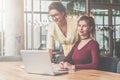 First girl is standing near table,second is sitting next to her.Teamwork.Girls blogging,working,learning online. Royalty Free Stock Photo