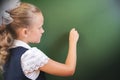 First grade schoolgirl wrote on blackboard with chalk at classroom