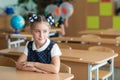 First-grader girl with bows on the first day of school at the Desk Royalty Free Stock Photo