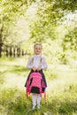 First-grader girl stands with a school pink backpack outdoors