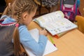 First-grader at a lesson of mathematics writes in a notebook, side view from the back Royalty Free Stock Photo