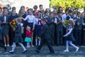 First-graders with bouquets of flowers are in front of high school students on the day of knowledge September 1