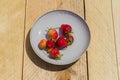 First harwest of garden strawberry on a plate on wooden background