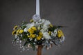 First holy communion flower bouquets. White candle decorated with white,and yellow flowers. Grey backgroud