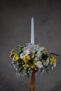 First holy communion flower bouquets. White candle decorated with white,and yellow flowers. Grey backgroud