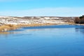 First ice on lake, withered reeds and hills with autumn yellow grass under snow and forest Royalty Free Stock Photo