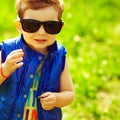 First investment concept. Portrait of stylish happy red-haired baby boy holding silver and golden coins in hand in the park. Royalty Free Stock Photo