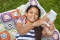 But first lemme take a selfie. a young girl taking a selfie while lying on a blanket in the outdoors. Royalty Free Stock Photo