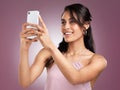 But first let me take a selfie. a beautiful young woman holding up her mobile phone to take a selfie against a pink Royalty Free Stock Photo