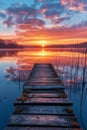 The first light of dawn illuminates a serene wooden dock overlooking a smooth lake with a beautiful sunrise. Royalty Free Stock Photo