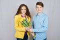 First love concept. Teen boy gives his girlfriend a bouquet of yellow tulips on white background. Royalty Free Stock Photo