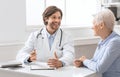 Friendly geriatrician talking with female patient, filling medical history