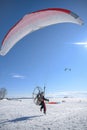 The first moments of taking off a motor paraplane over a large snow covered lake in bright sunny weather