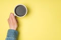 First person top view photo of female hand holding white cup of coffee on isolated yellow background with copyspace Royalty Free Stock Photo