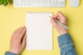 First person top view photo of female hands holding pen over open notebook plant white keyboard mouse on isolated yellow Royalty Free Stock Photo