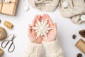 First person top view photo of female hands in sweater holding big decorative snowflake giftbox scarf christmas tree balls cones Royalty Free Stock Photo