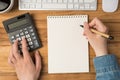 First person top view photo of female hands touching calculator and holding pen over notepad cup of coffee keyboard mouse on Royalty Free Stock Photo