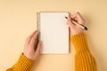 First person top view photo of female hands in yellow pullover writing in spiral notepad on isolated light orange background with Royalty Free Stock Photo