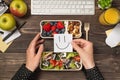 First person top view photo of hands holding sticky note with drawn smiling face over lunchboxes with healthy food apples glass of Royalty Free Stock Photo