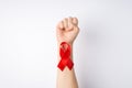 First person top view photo of raised female hand with clenched fist and red ribbon on wrist symbol of aids awareness on 