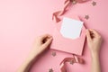 First person top view photo of st valentine`s day decor girl`s hands holding open pink envelope with letter glowing stars and pi