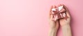 First person top view photo of valentine`s day decorations female hands giving small white giftbox with pink ribbon bow on Royalty Free Stock Photo