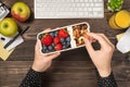 First person top view photo of woman`s hands holding lunchbox with healthy meal nuts and berries over apples glass of juice Royalty Free Stock Photo