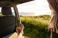 First-person view of a barefoot man relaxing inside a camper van and enjoying the view over the sea at sunset