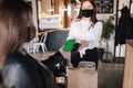 First person view of female paying with smartphone during Covid-19 pandemic. Cashier hand holding credit card reader