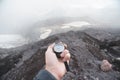 A first-person view of a man`s hand holding a magnetic compass against the background of the snow-capped mountains of Royalty Free Stock Photo