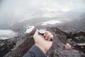 A first-person view of a man`s hand holding a magnetic compass against the background of the snow-capped mountains of Royalty Free Stock Photo