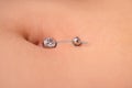 The first piercing. Dressing the earrings on the navel. Female piercing. Royalty Free Stock Photo