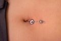 The first piercing. Dressing the earrings on the navel. Female piercing. Royalty Free Stock Photo