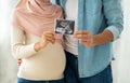 First portrait of our baby. Happy muslim pregnant woman and her husband showing sonogram picture to camera