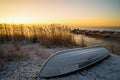 The first rays of the sun over lake Ladoga in the morning in winter. An overturned boat on a snowy beach