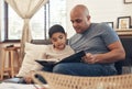 First we read, then we succeed. an adorable little boy reading a book with his father on the sofa at home. Royalty Free Stock Photo