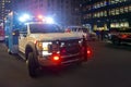 First responder ambulance on urban city street with lights flashing at night