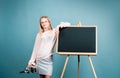 First of September. Day of knowledges. Cute blonde girl standing near blackboard wearing a school uniform. Pretty little