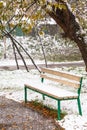 First snowfall and empty bench in city park Royalty Free Stock Photo