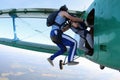 Skydivers are jumping out of a green biplane.