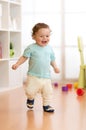 First steps of baby boy toddler learning to walk in living room. Footwear for little children. Royalty Free Stock Photo