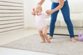 First steps of baby toddler learning to walk in white sunny living room. Footwear for child. Royalty Free Stock Photo