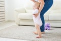 First steps of baby toddler learning to walk in white sunny living room. Footwear for child. Royalty Free Stock Photo