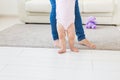 First steps of baby toddler learning to walk in white sunny living room. Footwear for child. Royalty Free Stock Photo