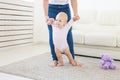 First steps of baby toddler learning to walk in white sunny living room. Footwear for child. Royalty Free Stock Photo