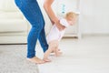 First steps of baby toddler learning to walk in white sunny living room. Footwear for child. Royalty Free Stock Photo