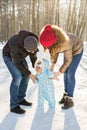 First steps. Little baby learning to walk. Mother and father with toddler boy at the winter park Royalty Free Stock Photo