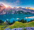 First sunlight gloving mountain hills and meadows. Picturesque summer view of unique Oeschinensee Lake. Sunrise in Swiss Alps with Royalty Free Stock Photo