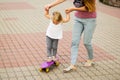 The first trip on the skateboard. Mom teaches a little girl to ride